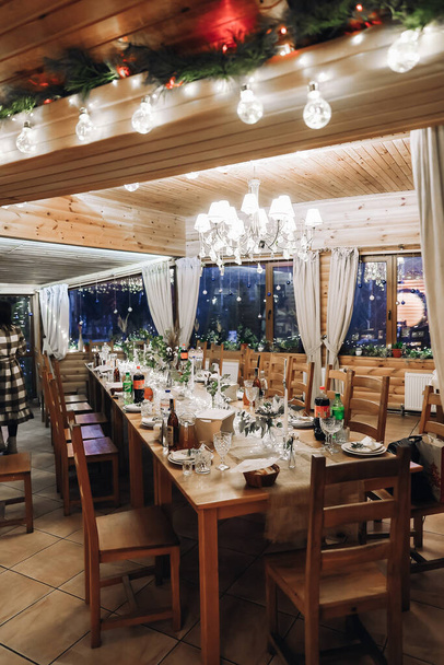 Glasses, flowers, fork, knife served for dinner in restaurant with cozy interior, retro film filter effect. High quality photo - Φωτογραφία, εικόνα