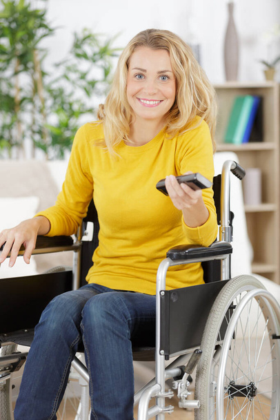 cheerful disabled woman watching television in living room - Photo, image