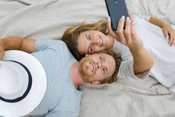couple taking selfie on hotel bed - Photo, image