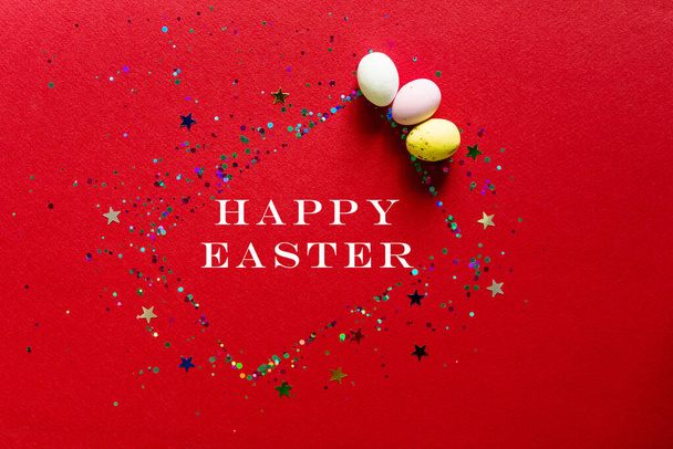 Happy easter decor concept. Blank greeting card, invitation mockup. Festive pastel red background, chocolates in the form of Easter eggs. Copy space, flat lay, top view. - Foto, Bild