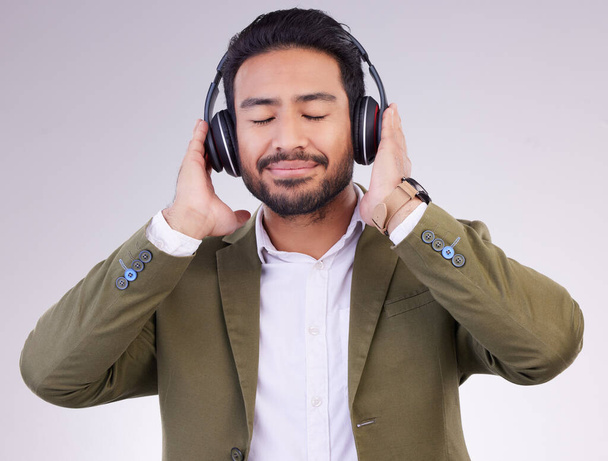 Music, relax and headphones with a business man in studio on a gray background streaming audio. Peace, quiet and calm with a male employee listening to the radio during a mental health break. - Photo, image