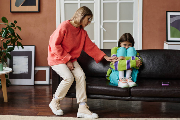 Молодая мать разговаривает со своим ребенком-подростком, пока она сидит на диване в плохом настроении - Фото, изображение