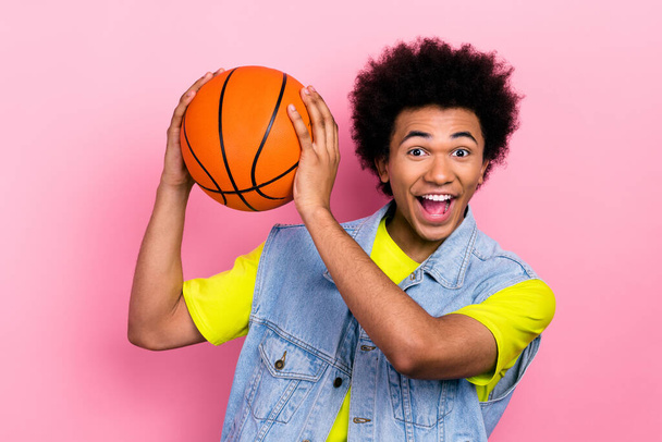 Fotografie nadšené funky člověk ruce držet basketbal otevřená ústa dobrá nálada izolované na růžovém pozadí. - Fotografie, Obrázek