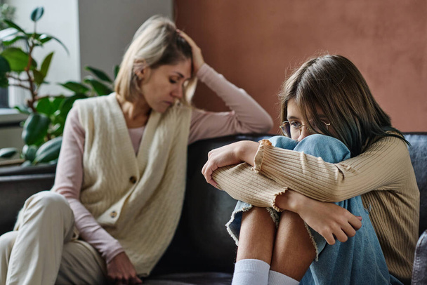 Rozrušený dospívající dívka ignoruje konverzaci se svou matkou, zatímco oni sedí na pohovce v místnosti - Fotografie, Obrázek