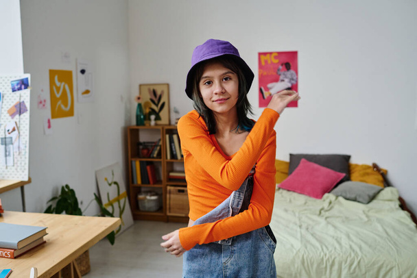 Retrato de adolescente olhando para a câmera enquanto filma vídeo para seu blog em pé em seu quarto - Foto, Imagem