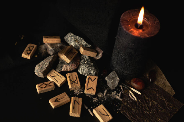 runas de madera sobre un fondo oscuro con una vela y piedras de ámbar, para un ritual mágico - Foto, Imagen