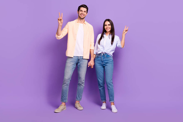 Full body portrait of two cheerful partners hold arms demonstrate v-sign isolated on purple color background. - Fotografie, Obrázek