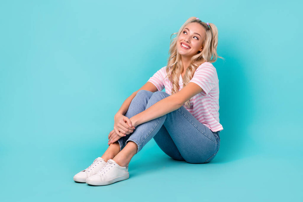 Full length photo of friendly girl striped t-shirt denim pants siting look empty space sale isolated on vivid turquoise color background. - Fotó, kép
