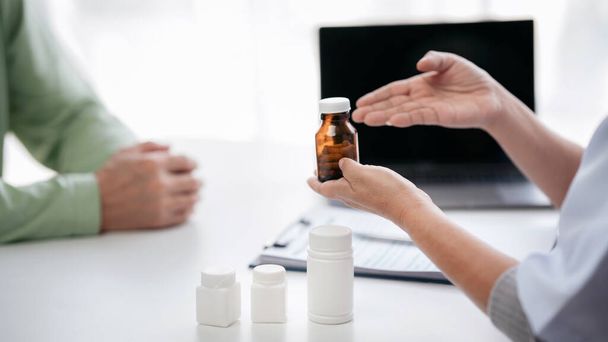 Ärztin zeigt Flasche Pillen, um Medikamentengebrauch zu erklären und nach körperlicher Untersuchung für ältere Patienten im Krankenhaus die Gesundheitsfürsorge zu konsultieren. - Foto, Bild