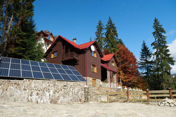 Renewable energy. Solar cell panels on the fence near wooden house in village - Valokuva, kuva