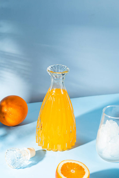 Zumo de naranja fresco con hielo en un vaso sobre fondo azul. cóctel naranja - Foto, Imagen