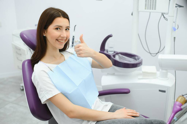 The girl is at the reception at the dentist. A happy client at the dentist smiles. . Dental bleaching. Dental clinic. Treatment of teeth in a modern clinic. Restoration of a healthy smile. Successful. - Photo, image