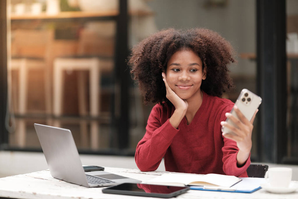 Amerikanische Afroamerikanerin arbeitet im Freien mit Computertelefon und Tablet. Hochwertiges Foto - Foto, Bild