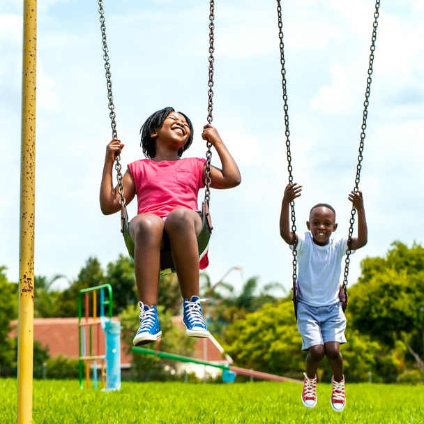 African kids having fun swinging in park. - Valokuva, kuva