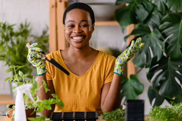 Afrikaans amerikaanse vrouw bloemist verzorgen van planten  - Foto, afbeelding