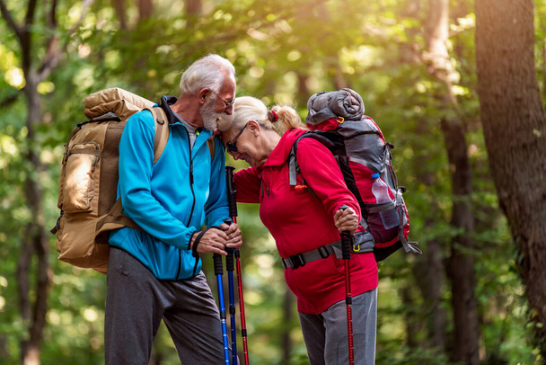 Старшая пара с рюкзаками на походы весело провести время в природе. Любовь, люди, природа и образ жизни. - Фото, изображение