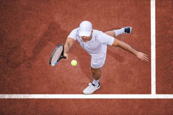 Du sport. Vue du dessus du joueur de tennis masculin frappant la balle avec la raquette. - Photo, image