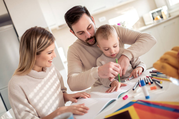 Mère et père dessinent ensemble avec leur enfant à la maison. - Photo, image