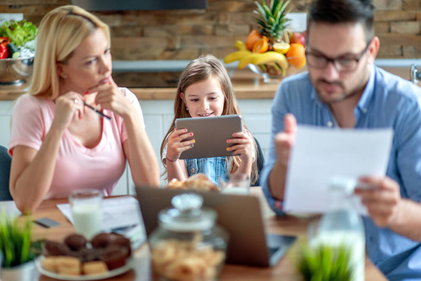 Portrait de jeune famille calculant ses factures avec sa fille à la maison. - Photo, image