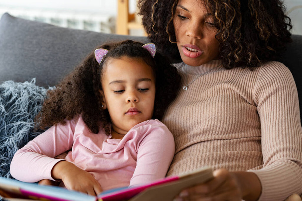 african american daughter and mother reading book - Foto, imagen