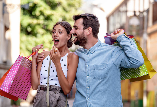 Πορτρέτο του ευτυχισμένου ζευγαριού με τσάντες ψώνια μετά τα ψώνια στην πόλη. - Φωτογραφία, εικόνα