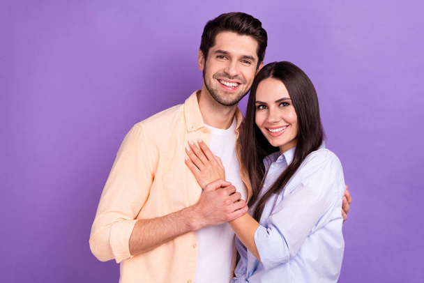 Photo portrait of young lovely positive couple hugs together wear casual shirt hands together harmony idyllic isolated on violet color background. - Zdjęcie, obraz