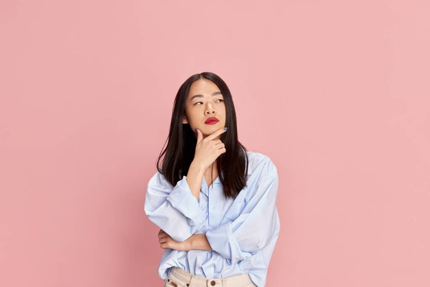 Ideas. Portrait of young korean girl in casual clothes posing with thoughtful face against pink studio background. Concept of emotions, facial expression, fashion, youth, lifestyle. Ad - Foto, Imagem