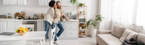 Young african american woman hugging bearded boyfriend in kitchen, banner  - Foto, immagini