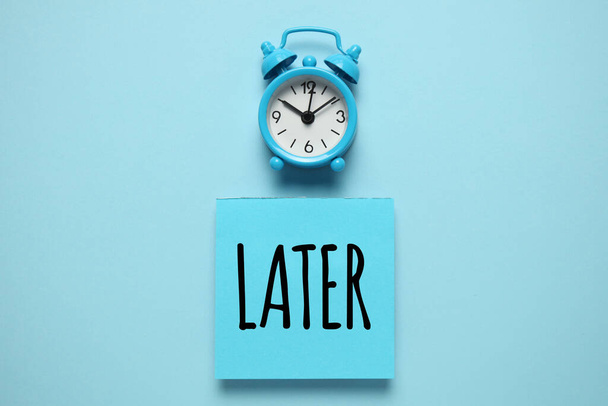 Blue alarm clock and paper reminder, later. Time management, priorities, efficiency, control and goals. - Foto, imagen