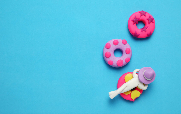 Plasticine people relaxing on inflatable donut lilo in pool. Cartoon summer relaxing and holidays. - 写真・画像