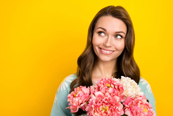 Photo of pretty dreamy lady dressed teal cardigan looking empty space holding flowers isolated yellow color background. - Foto, immagini