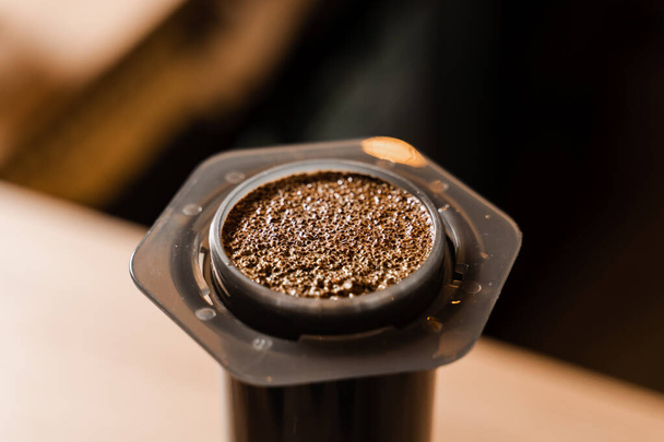 Close-up gemahlener Kaffee mit heißem Wasser in der Aeropress. Prozess der Aeropress alternative Methode Kaffee brauen. Heißes Wasser über geröstete und gemahlene Kaffeebohnen in der Aeropress gießen - Foto, Bild