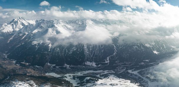 Alpine landscape with peaks covered by snow and clouds. Magical clouds covering peaks of the mountains at the famous St. Anton am Arlberg ski resort. - Fotografie, Obrázek