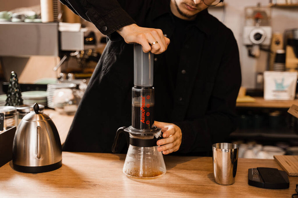 Aeropress-Kaffee. Barista treibt Aeropress dazu an, Kaffeetropfen von Aeropress in Topf zu gießen. Alternative skandinavische Kaffeebrühmethode - Foto, Bild