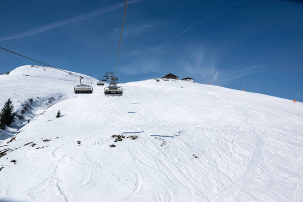Pass Thurn, Austria - Zimą wyciąg krzesełkowy dla narciarzy wchodzi na zaśnieżone wzgórze. - Zdjęcie, obraz