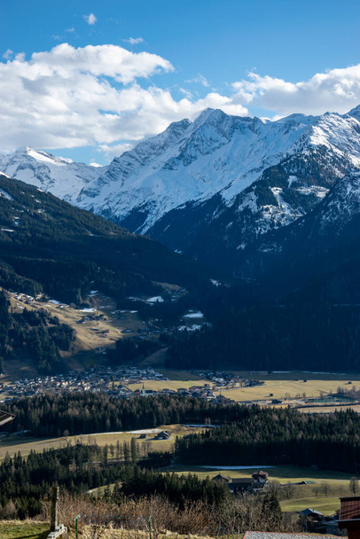 A valley in the Austrian Alps, snowy peaks of rocky mountains and a valley with meadows and a village. - Foto, imagen