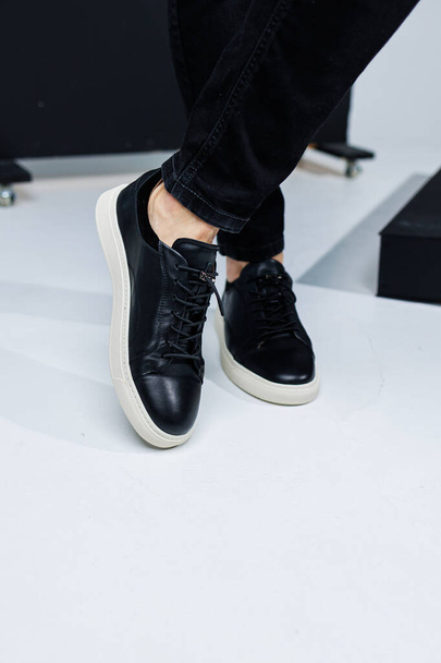 Close-up of male legs in black leather casual sneakers. Comfortable men's demi-season shoes - Photo, Image