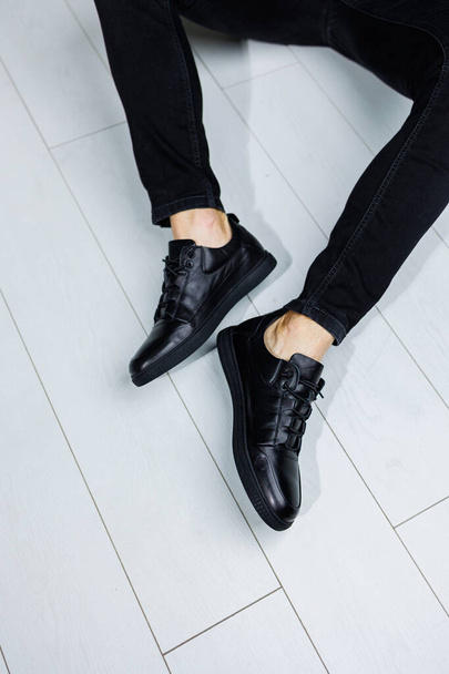 Primo piano delle gambe maschili in pelle nera casual sneakers. Scarpe comode da uomo demi-season - Foto, immagini
