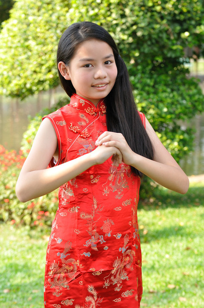 Asie adolescente porter costume rouge pose pour prendre des photos dans le jardin
 - Photo, image