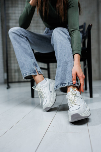 Detailní záběr ženských nohou v džínách a botách v módních teniskách zblízka. Dámské každodenní módní boty. - Fotografie, Obrázek