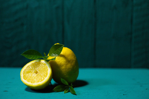 Fresh lemons with green leaves on a beautiful dark background, front view. - Fotografie, Obrázek