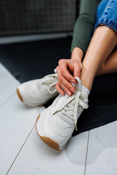 Sports shoes for women. Slender female legs in jeans and white stylish casual sneakers. Women's comfortable summer shoes. Casual women's fashion - Φωτογραφία, εικόνα
