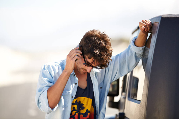 I need a little help out here. A young man phoning for roadside assistance - Foto, Imagem