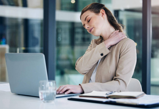 My body is taking a beat with all these deadlines. a young businesswoman experiencing neck pain while working on a laptop in an office - Photo, image