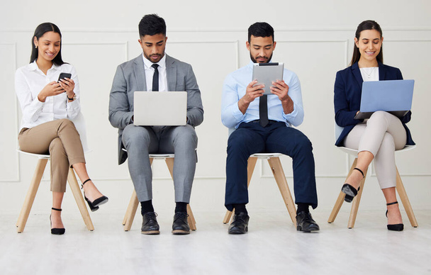Group of diverse businesspeople waiting for interview and using technology. Team of young applicants sitting together. Professional candidates in line for job opening, vacancy and office opportunity. - Foto, Bild