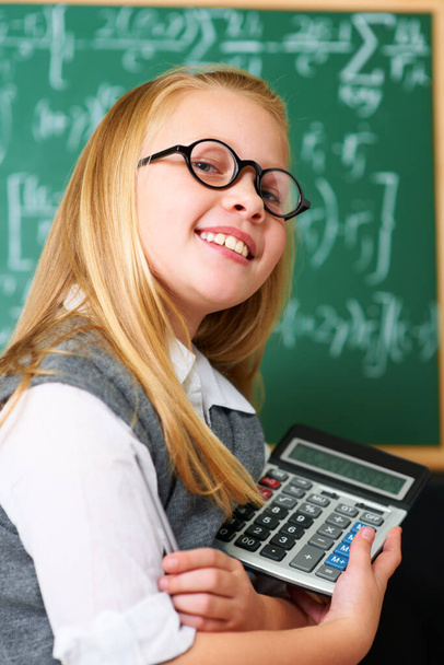 Happy with the solution. A cute blonde girl with a pen and calculator in class - Photo, image