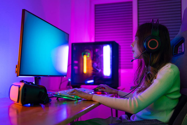 Asyalı bir kadının çevrimiçi video oyunu oynadığı oyuncu ve E-Sport çevrimiçi ışıklandırma efektiyle, evinde canlı yayın yapıyor. Oyuncu ve E-Sport çevrimiçi oyun teknolojisi şampiyonluğu turnuvası. - Fotoğraf, Görsel