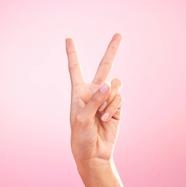 Žena, ruce a mírové znamení, emoji nebo symbol pro svobodu na růžovém pozadí studia. Ruka ženy ukazující mírumilovnou ikonu V nebo tvar pro naději, podporu nebo důvěru v hlasování nebo hlas na maketě. - Fotografie, Obrázek