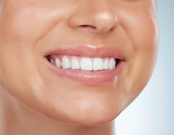 Zbliżenie nieznanej kobiety uśmiechającej się białymi zębami po zabiegu wybielania. Szczęśliwy biały model odizolowany na szarym tle w studio i wykazujący doskonałą higieny jamy ustnej rutynowych i opieki. - Zdjęcie, obraz