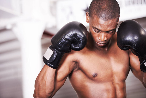 Osamělý a připravený k boji. Africký americký boxer shlíží dolů s rukavicemi nahoře - Fotografie, Obrázek
